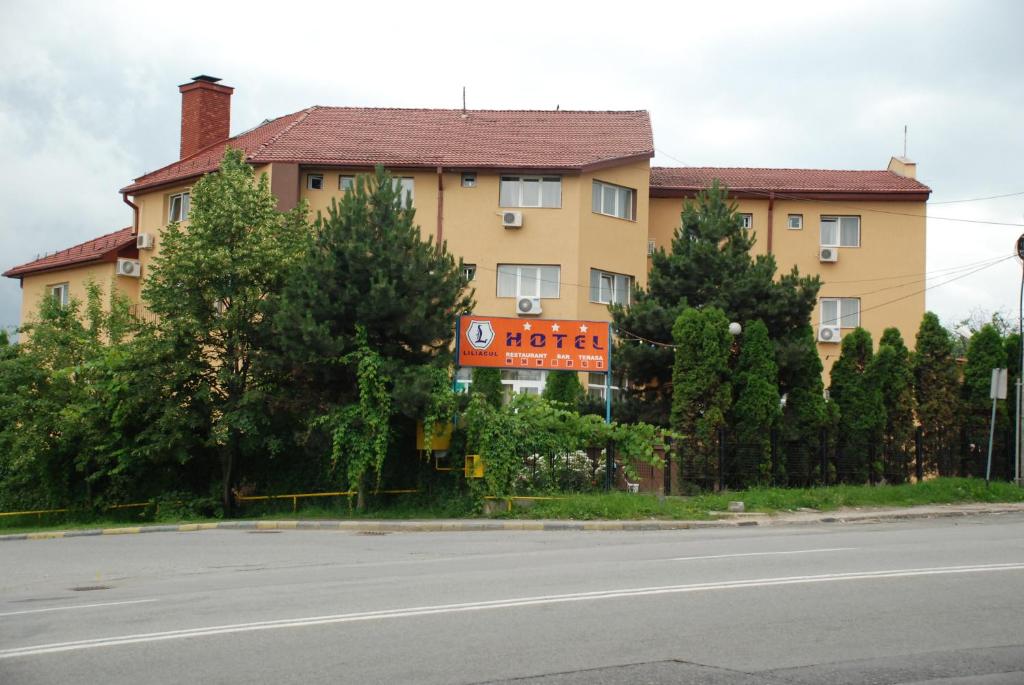 a building on the side of a road with trees at Hotel Liliacul in Cluj-Napoca