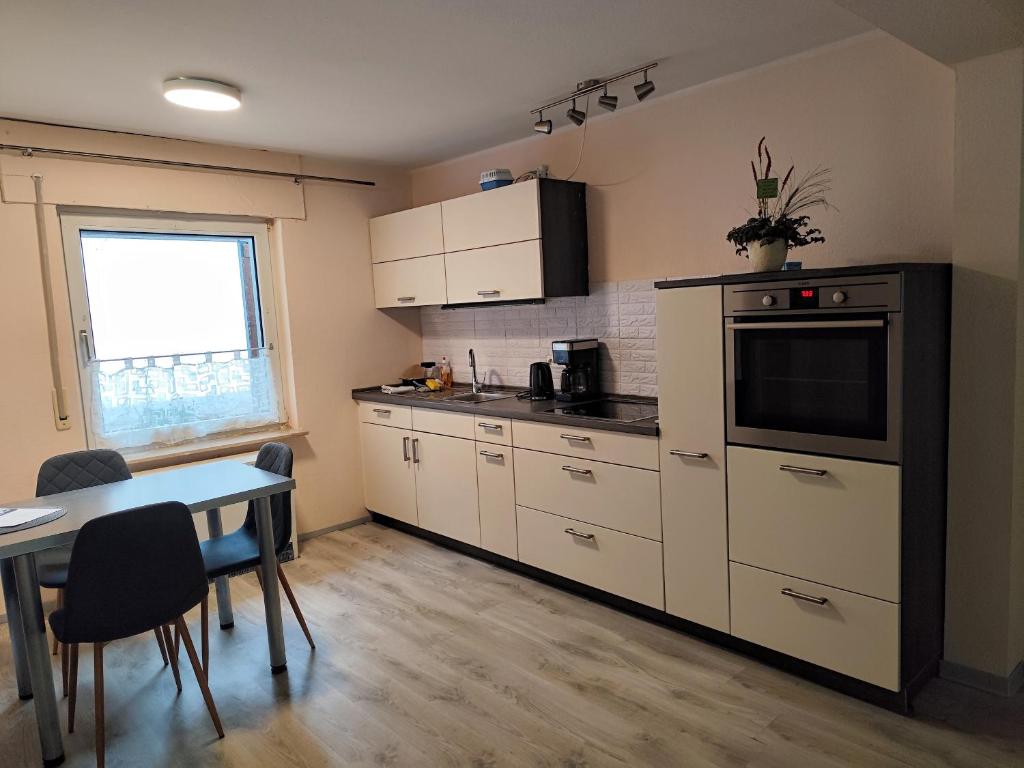 a kitchen with white cabinets and a table and a window at Gästehaus Ruhepol in Bissendorf