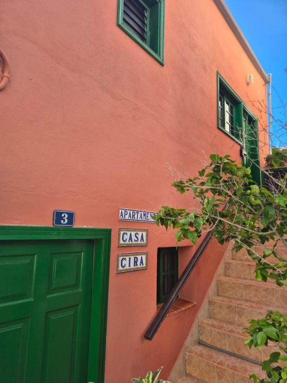 an orange building with a green door and stairs at Casa Cira in Calera