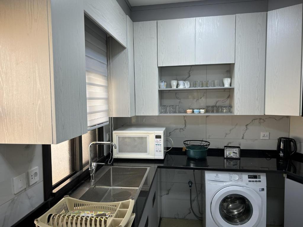 a kitchen with a washing machine and a microwave at golden apartment - karak - thaniyah الكرك الثنية in Kerak