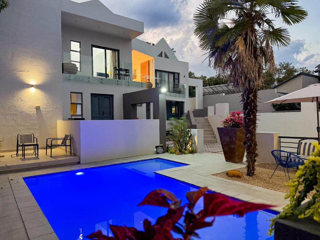 a villa with a blue pool in front of a house at Amoris Guesthouse I - Randburg in Johannesburg