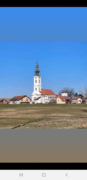 a white building with a clock tower in a field at Vila Vera in Futog