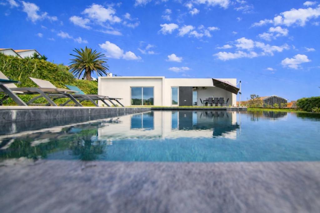 a swimming pool with a house in the background at Seaview Villa with Heated Private Pool in Bretanha