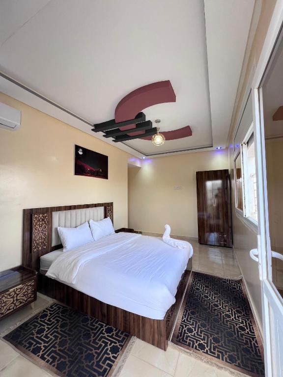 a bedroom with a large bed and a ceiling fan at Residence Almahaj in Laayoune