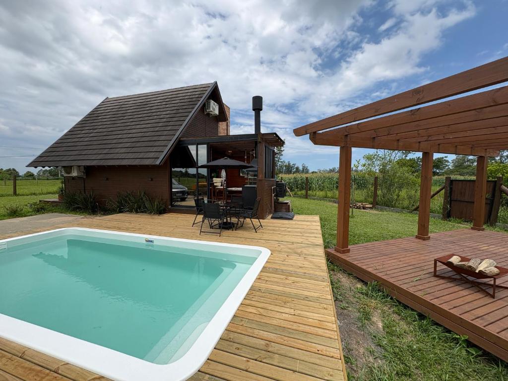 a swimming pool on a wooden deck with a house at Chalé Rústico com Piscina Aquecida e Hidro in Araranguá