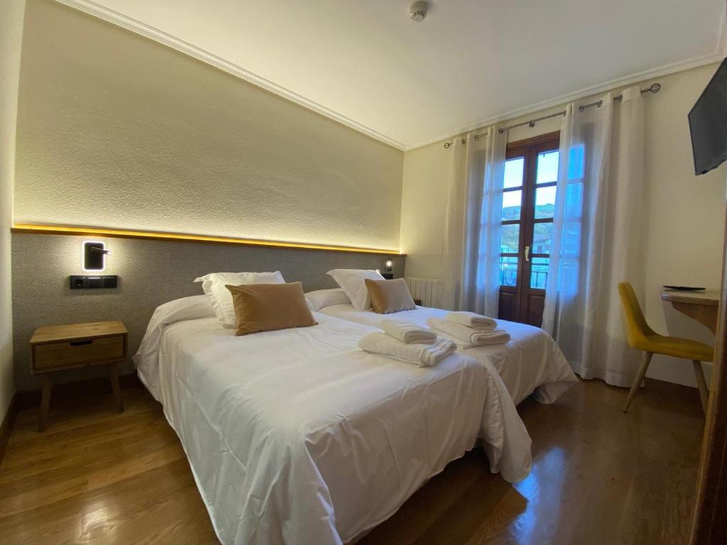 a bedroom with two beds with white sheets and a window at Hostal Restaurante Casa Santamaria in Doneztebe