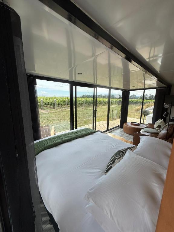 a bedroom with a bed with a view of a field at Ultimate Vineyard Escape - Waipara in Waipara