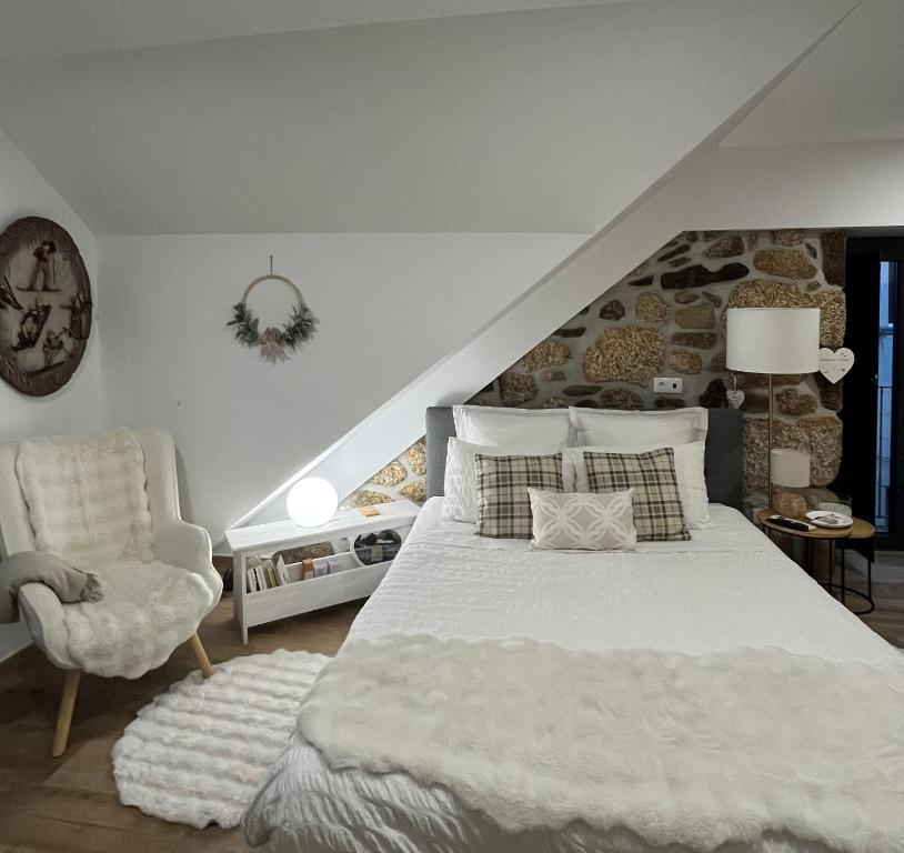 a bedroom with a white bed and a chair at Senhora da Estrela AL in Seia