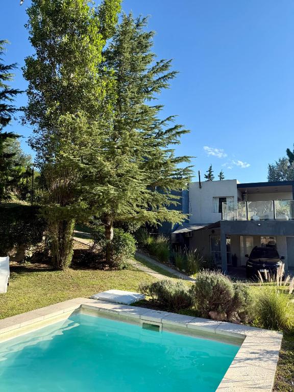 a blue swimming pool in front of a house at Altos del Oeste in Villa Carlos Paz