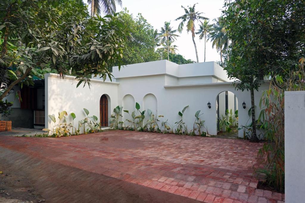 a white house with a red brick driveway at Kash Beach Villa, Varkala - Steps from Odayam Beach in Varkala