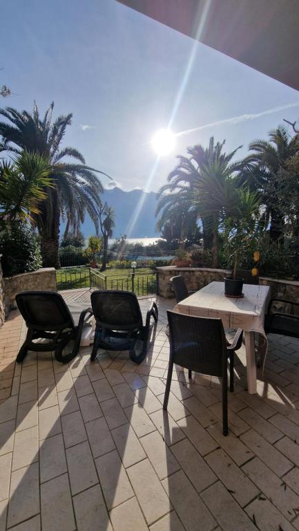 a patio with a table and chairs and palm trees at Appartamento A Limone in Limone sul Garda