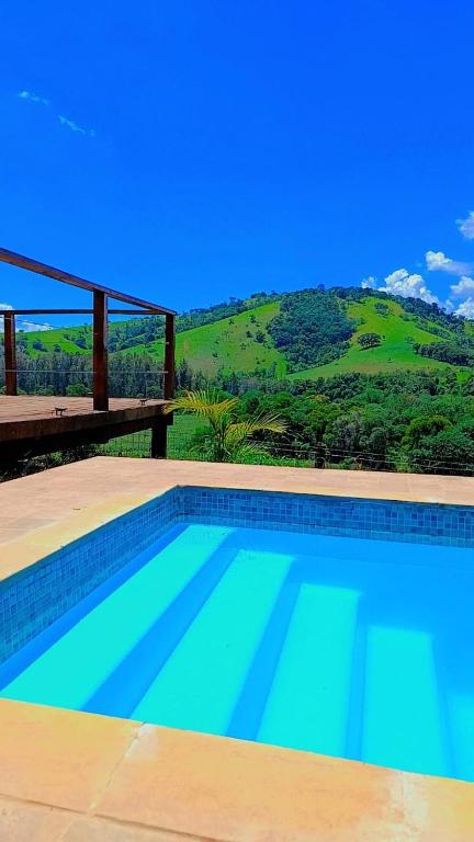 a swimming pool with a mountain in the background at Chácara Pôr do sol in Alfenas