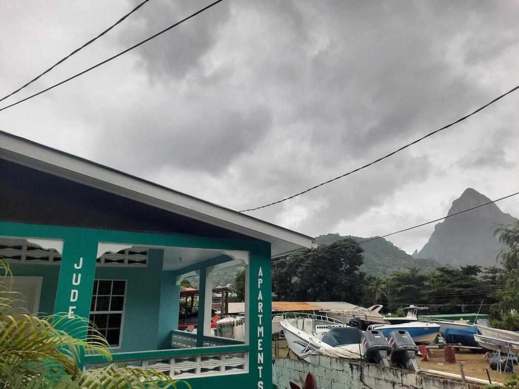 une maison avec des bateaux dans un port de plaisance avec une montagne dans l'établissement Jude Apartments, à Soufrière