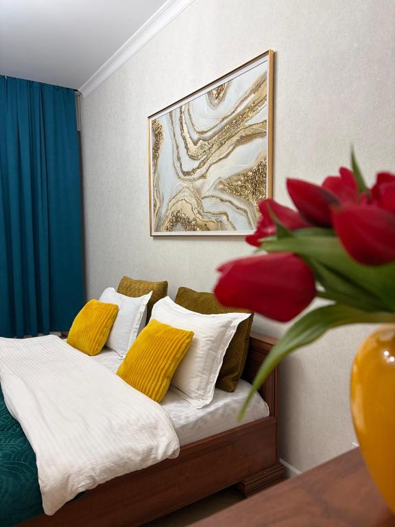 a bedroom with a bed and a vase with red flowers at Walk Everywhere & Tourist Pick & Центр Города Алматы in Almaty