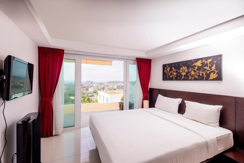 a bedroom with a large bed with red curtains at ELEGANT Kata sea View Apartmens in Kata Beach