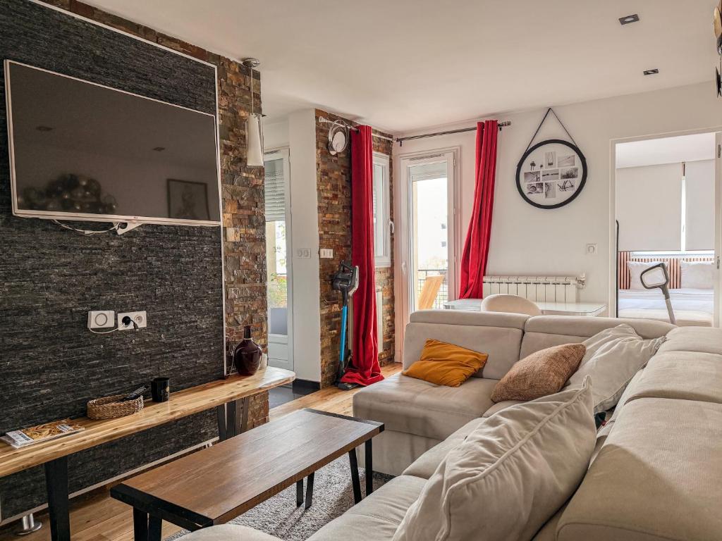 a living room with a couch and a tv at Appartement convivial pour séjourner in Le Kremlin-Bicêtre