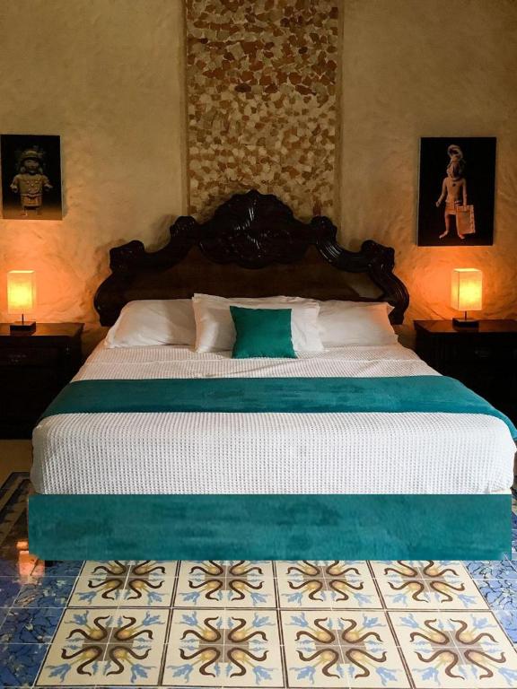 a large bed in a bedroom with two lamps at Casa Bahareque Merida in Mérida