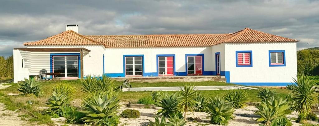 a small house with blue and red doors at Quinta Maria Cotovia in Porto Covo