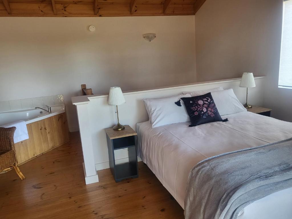 a bedroom with a bed and a bathroom with a sink at Denmark Waterfront Lodge in Denmark