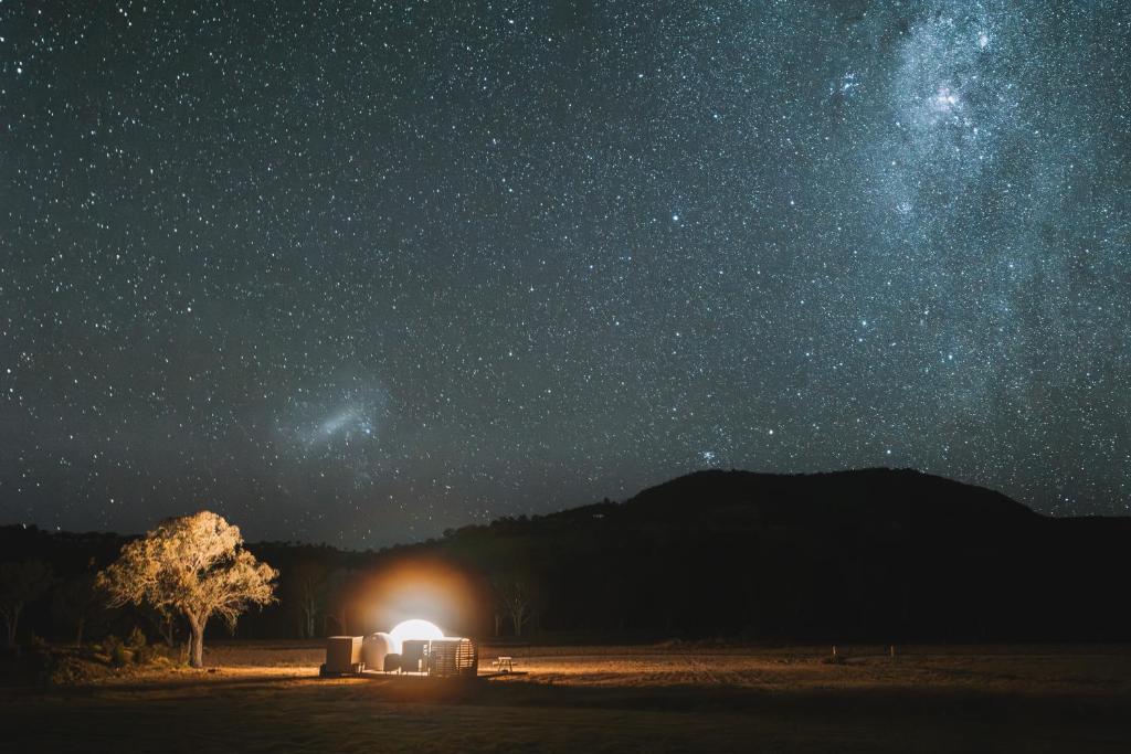 a night view of a starry sky with a lit up tent at Captain Moonlite Bubbletent at Mirumiru in Tenterfield