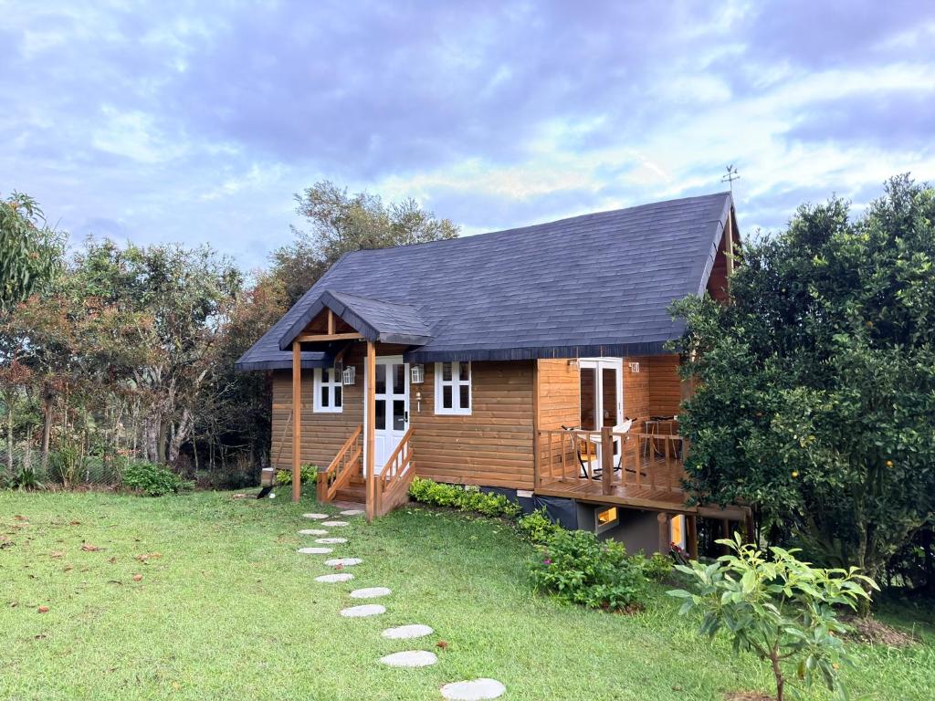 a log cabin with a porch and a grass yard at WOODEN HOUSE Hermoso alojamiento en Llanogrande Rionegro cerca a Medellín & Aeropuerto JMC in Rionegro