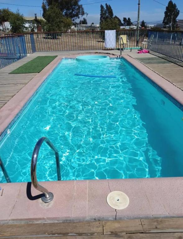 a swimming pool with blue water in a yard at Cabaña Quillaycillo in La Rudilla