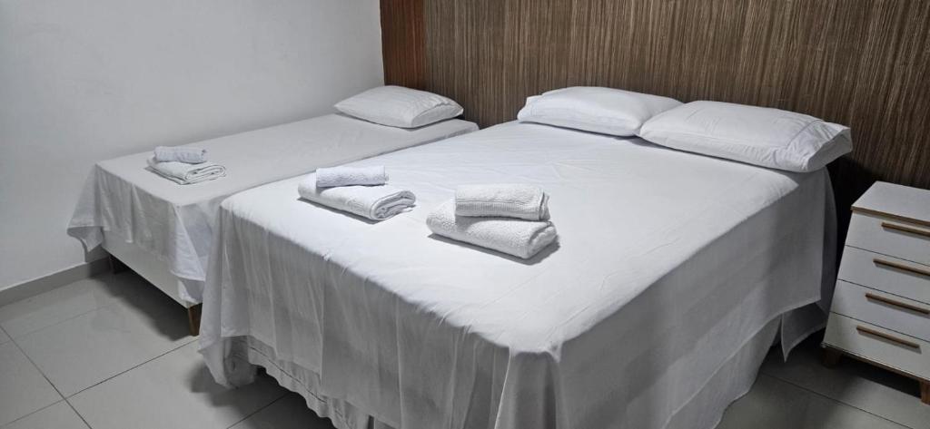 a bedroom with two beds with white sheets and towels at Residencial Carmo&Costa in Belém