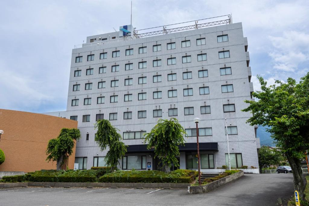 a white building with trees in front of it at ホテルグランフォーレ in Shikokuchuo