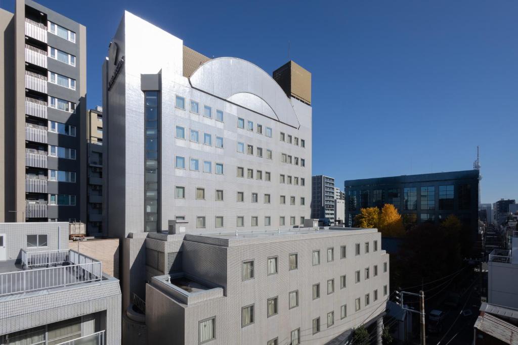 a large white building in a city with tall buildings at HOTEL MYSTAYS Ueno East in Tokyo
