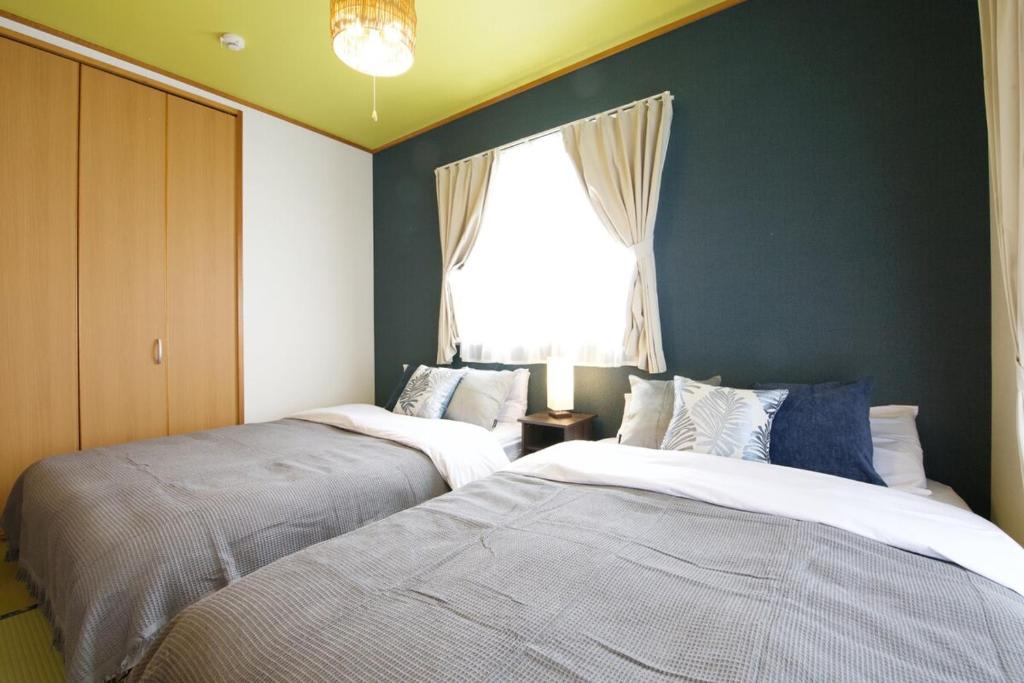 two beds in a room with a window at カラハーイもとぶ 2-3 in Motobu
