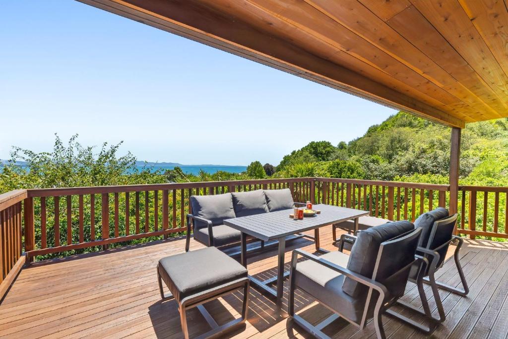a patio with a table and chairs on a deck at Kotare Heights in Pohara