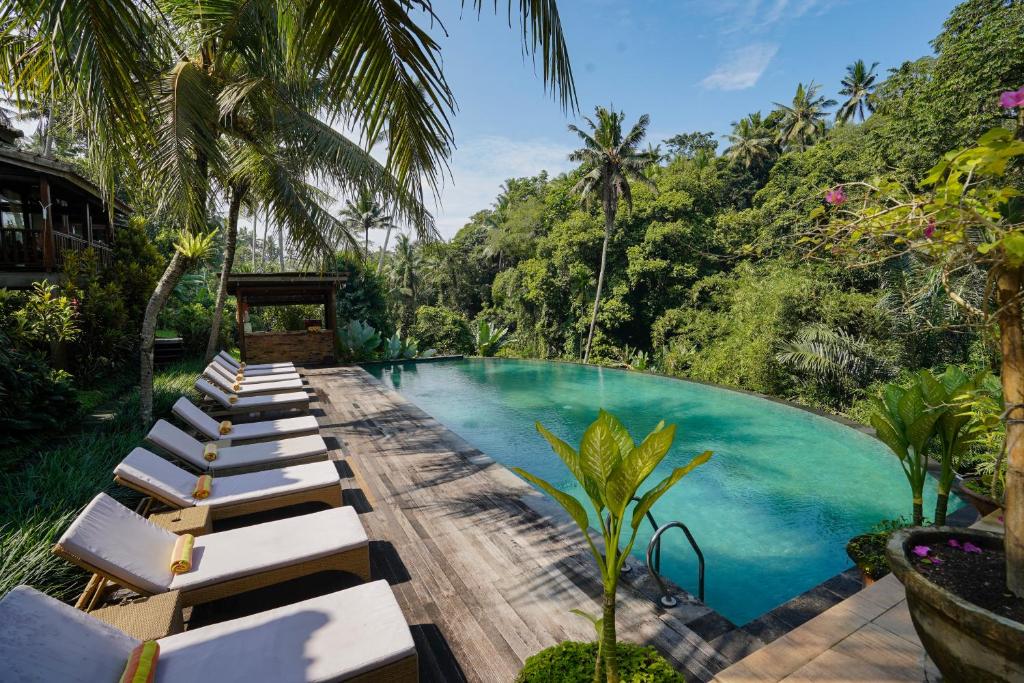 a pool with chaise lounge chairs next to a resort at Pertiwi Bisma 1 in Ubud