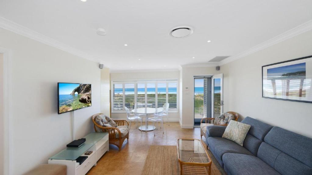 a living room with a blue couch and chairs at Pacific Court 'absolute Beachfront=' in Avoca Beach