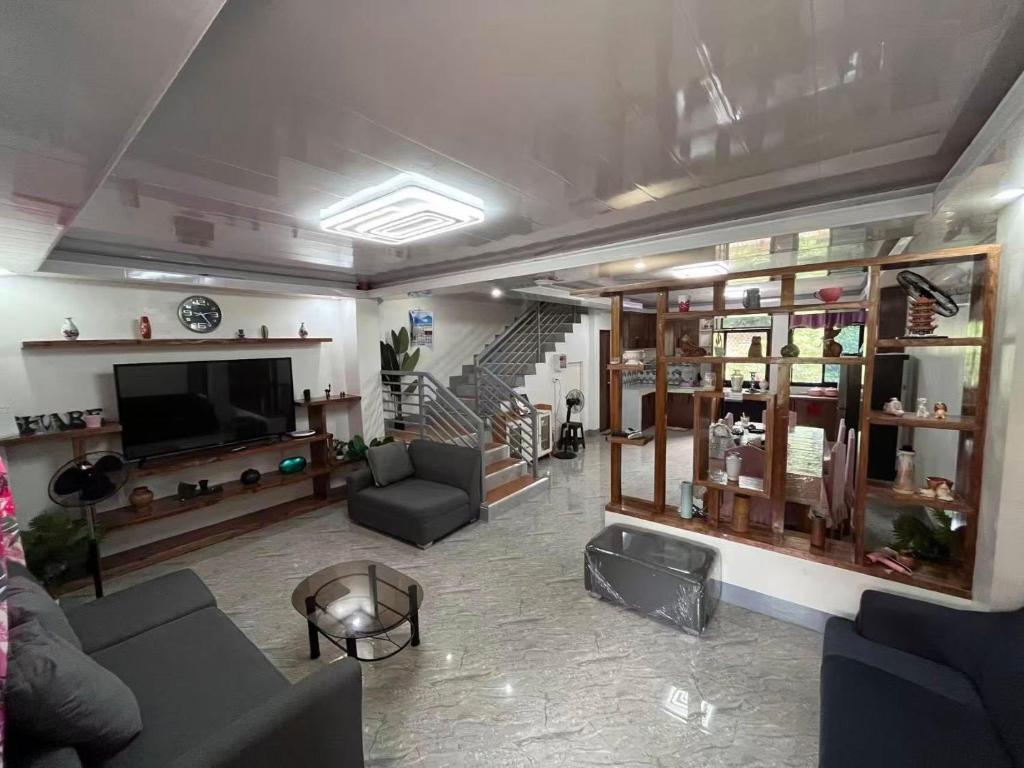 a living room with couches and a television and stairs at Two-Storey Townhouse in Laguindingan