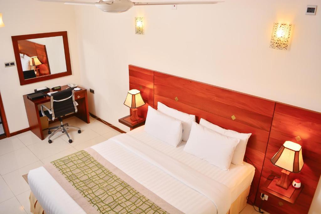 a bedroom with a bed and a desk and a mirror at Unique Towers Luxury Boutique Suites in Colombo