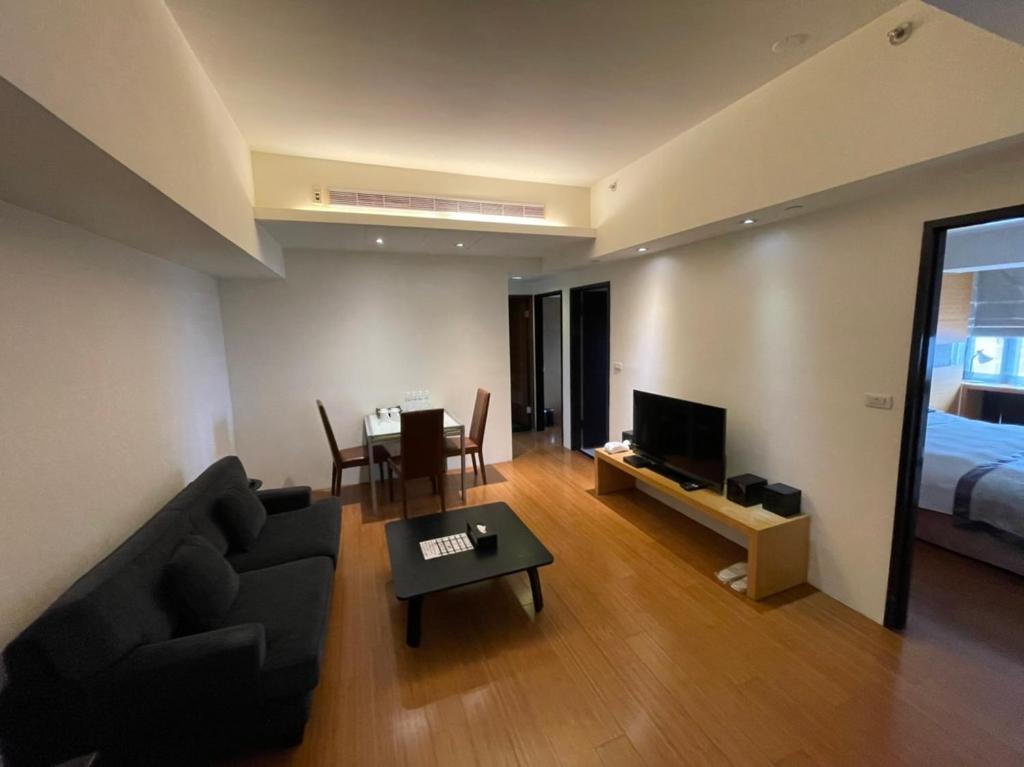 Master Hotel في تايبيه: غرفة معيشة بها أريكة وسرير وطاولة