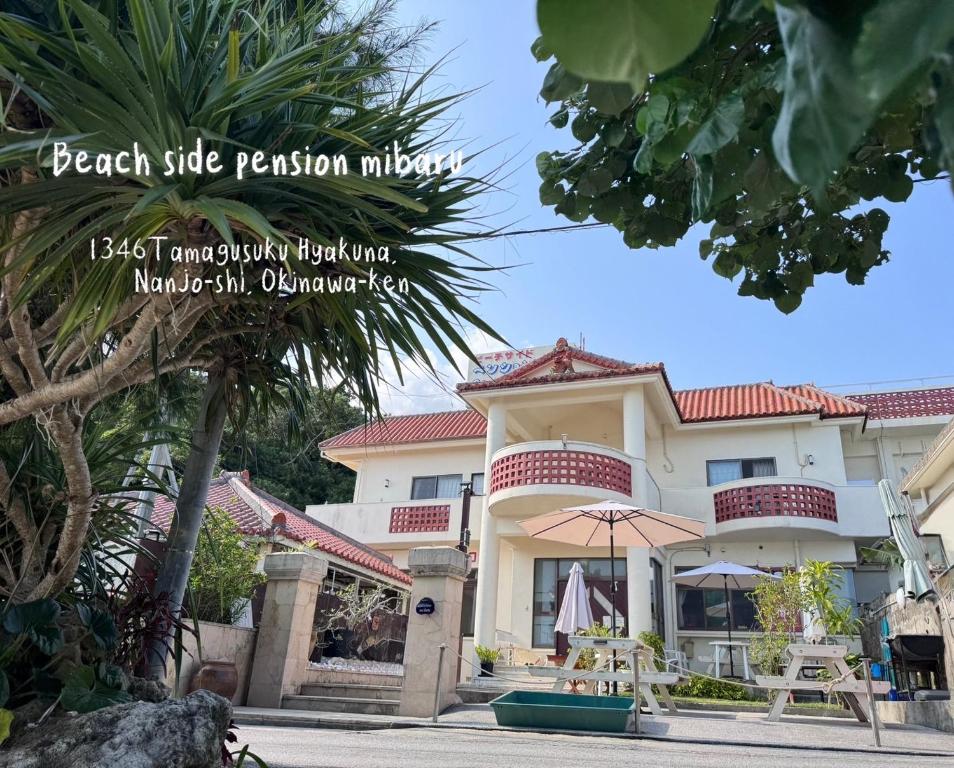 a house with a palm tree in front of it at Beachside Pension Mibal in Nanjo