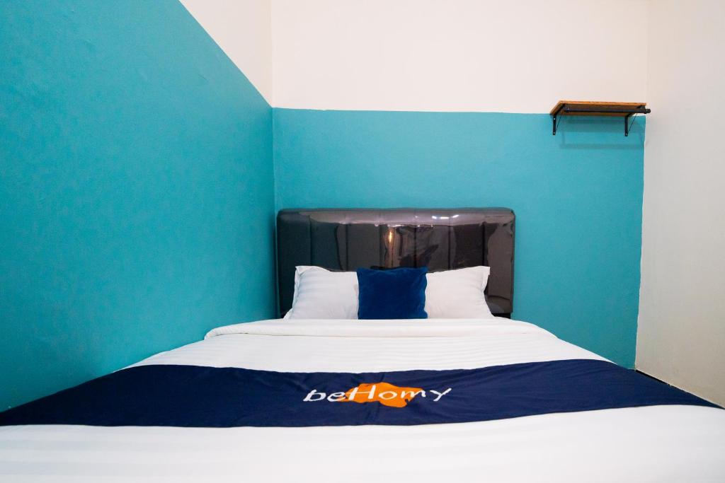 a bed in a room with a blue wall at Behomy Yume Grogol in Jakarta