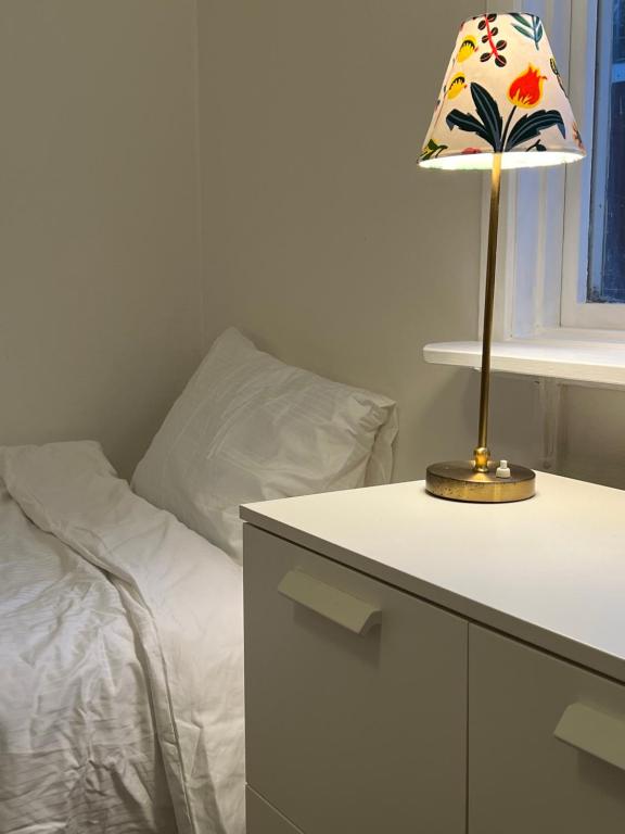 Eine Lampe auf einem Tisch neben einem Bett in der Unterkunft Kalvsvik in Värmdö