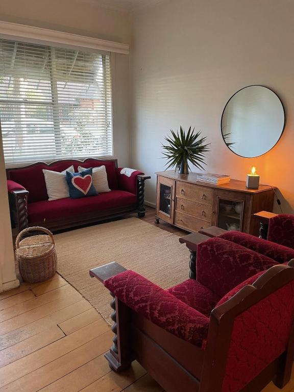 a living room with a red couch and a mirror at Stockton Coastal Escape in Stockton