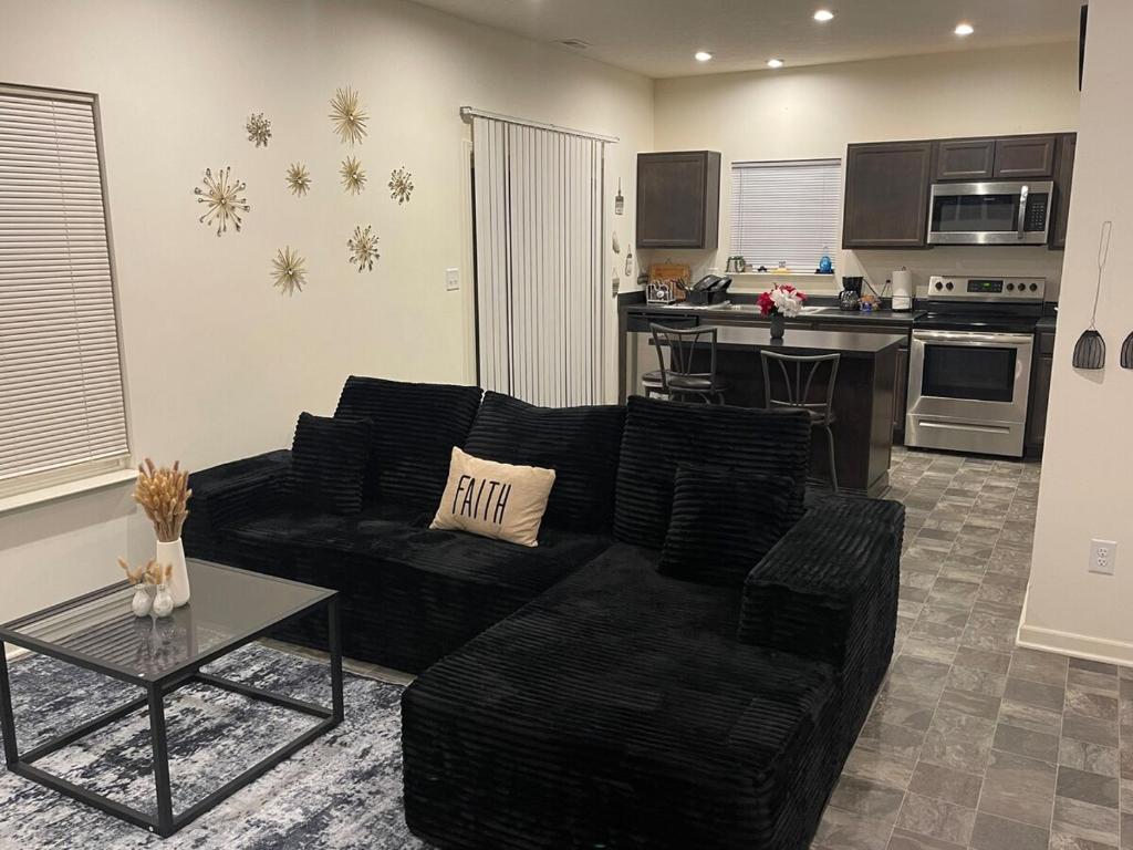 a living room with a black couch and a kitchen at Inner Haven Family Homes in Indianapolis