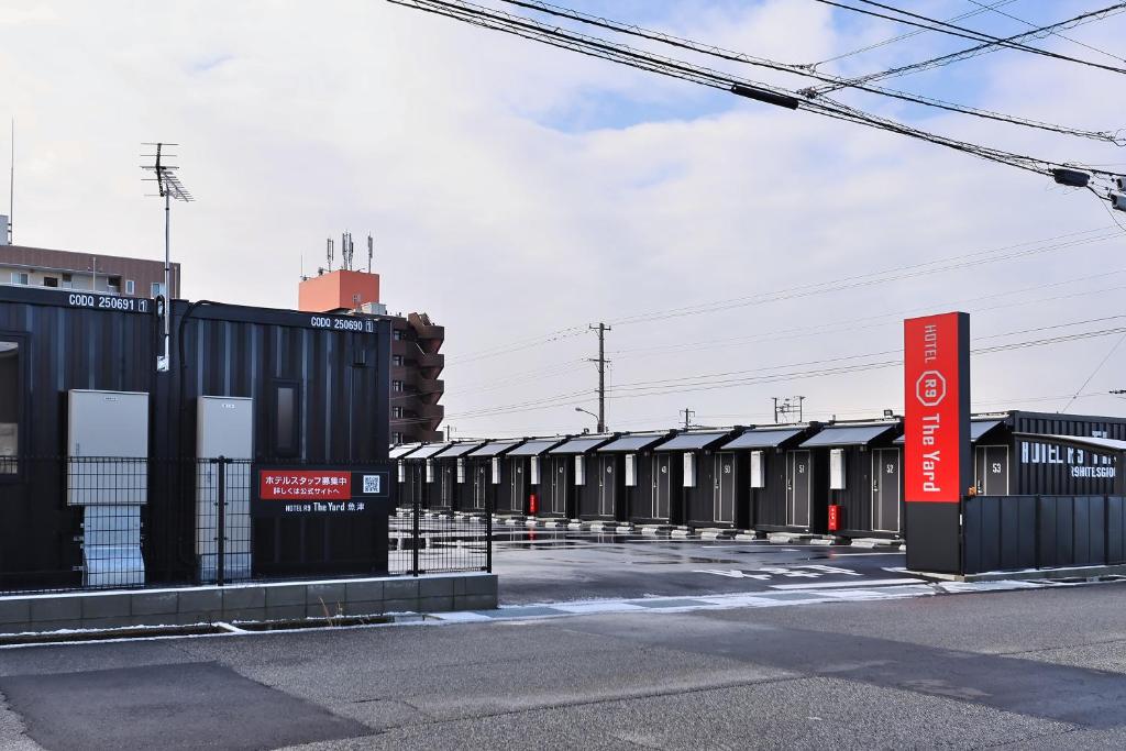 a row of black buildings with a red sign in front at HOTEL R9 The Yard Uozu in Motoshin