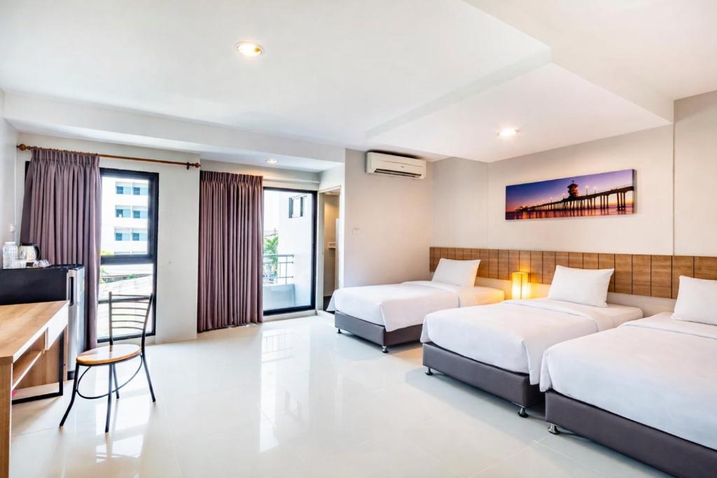 ein Hotelzimmer mit zwei Betten und einem Schreibtisch in der Unterkunft Aliz Hotel in Nonthaburi