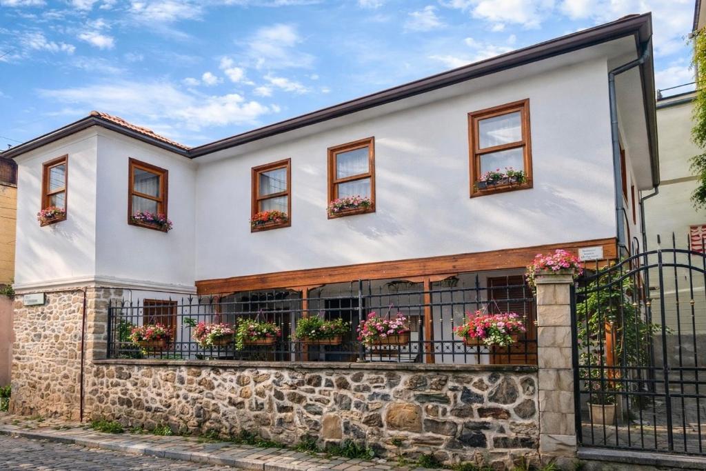 a white house with windows and flowerpots at Bujtina Kenedi in Korçë