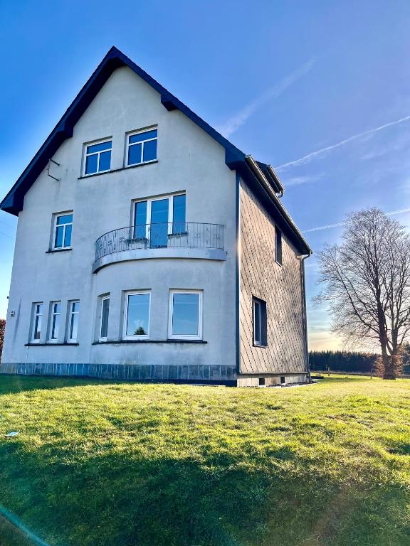 a large white house on a grass field at Ferienhaus Zum Brand in Butgenbach