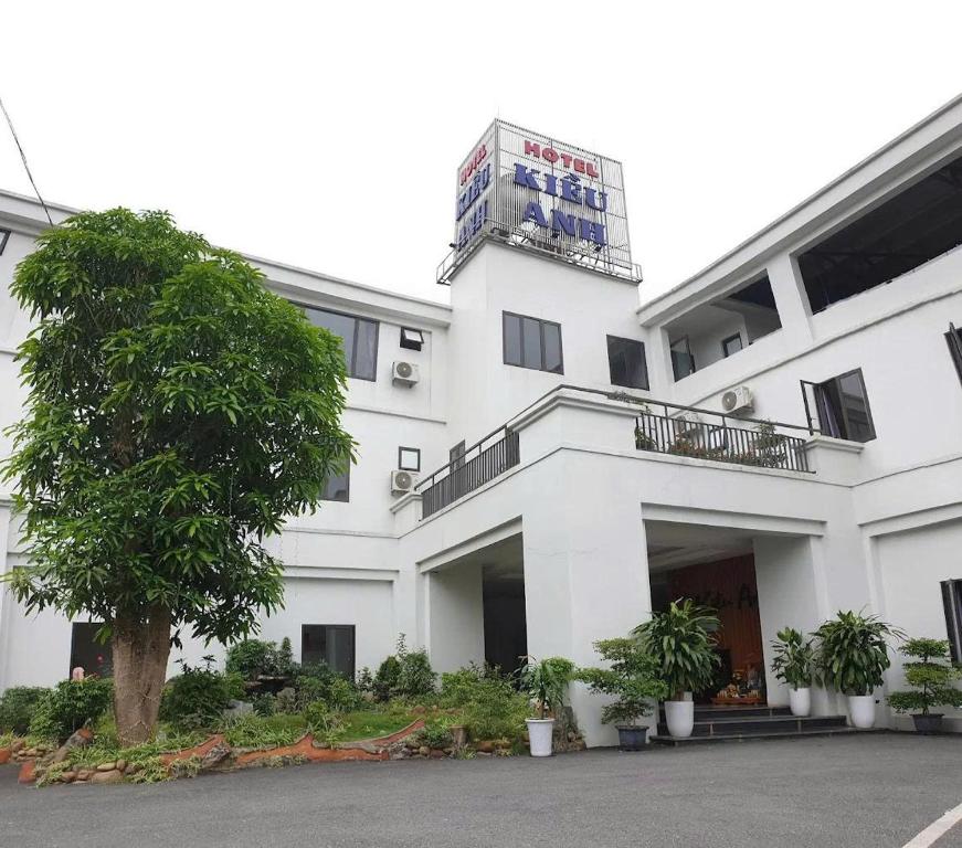 a white building with a tree in front of it at Kieu Anh Hotel Phu Tho in Thanh Sơn