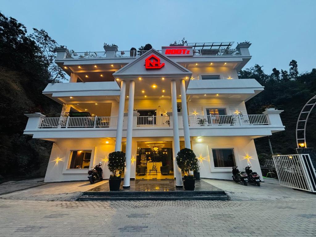 a large white building with a red sign on it at Rootz in Dehradun