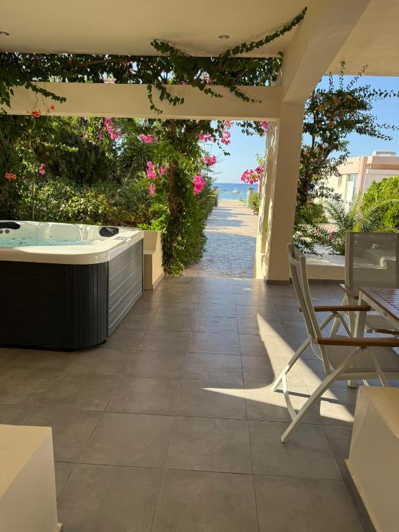 a patio with a hot tub and a view of the ocean at Amaryllis Beach House in Lartos