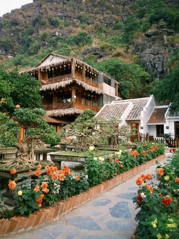 a building with a bunch of flowers in front of it at Hang Mua Ecolodge in Ninh Binh