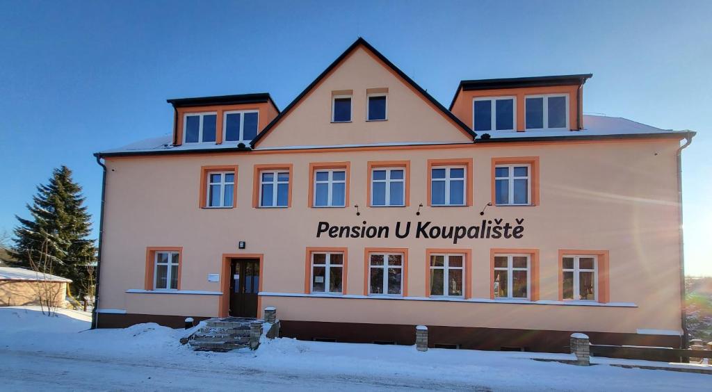 a large white building with a sign on it at Pension U Koupaliště in Tisá